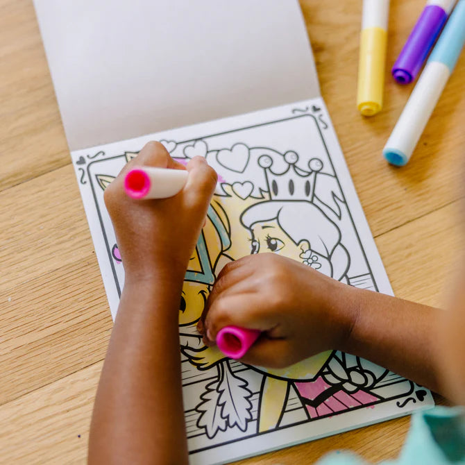 Child coloring a princess picture with markers on a wooden table