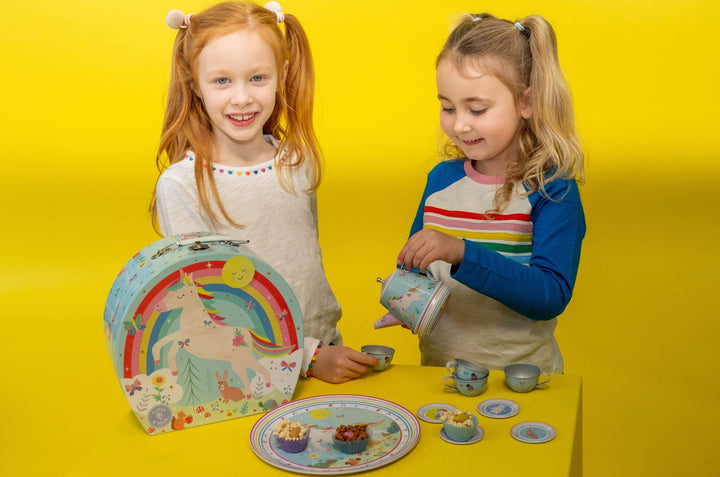 Two children playing with a tea set against a yellow background