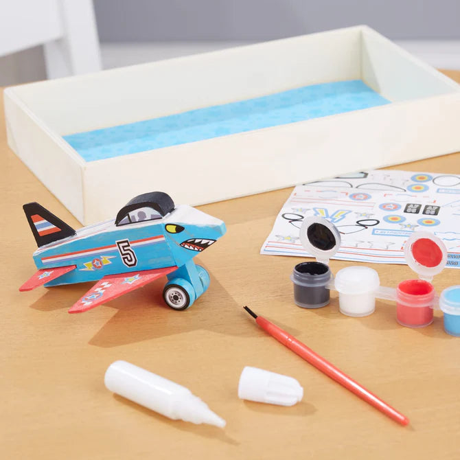 Children's toy airplane with paint supplies on a table